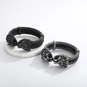 Detailed view of dual lion head charms on a black braided steel cable men's bracelet