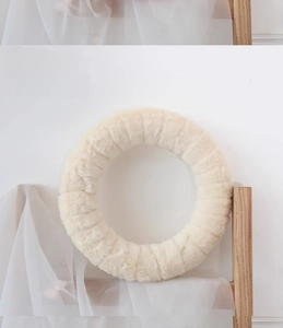 Detail of a fluffy cream white wool felt wreath hanging on a minimalist light wood stand