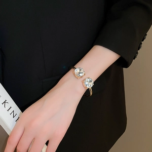 Detail of gold open cuff bracelet with two large cubic zirconia stones on model wrist
