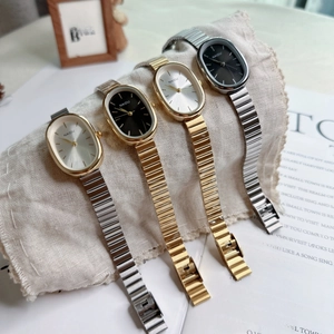 Detailed display of oval quartz watches with stainless steel bands on a rustic linen roll