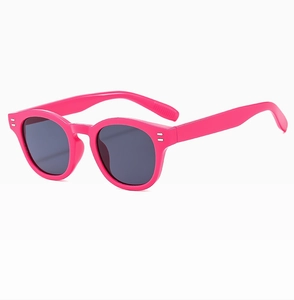 Detail view of pink oval frame sunglasses with silver double dot rivets and dark lenses