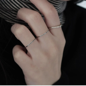 Close-up of minimalist 925 sterling silver stacked rings with wavy line designs