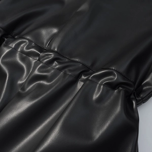 Gros plan sur la veste en simili cuir noir avec cordon de serrage et plis à la taille