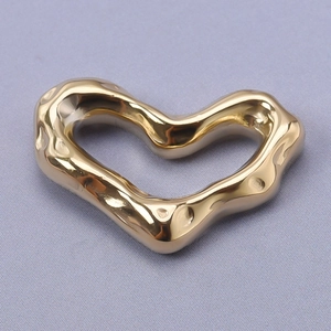 Macro shot of gold stainless steel heart pendant with hammered texture and hollow design