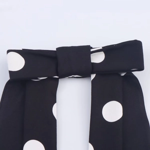 Detail view of a black top with white polka dots and a stylish bow knot design