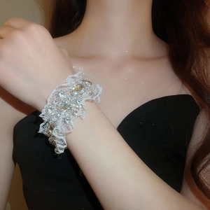 Détail d'un bracelet en dentelle blanche avec motifs raffinés et strass étincelants