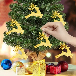 Detail of hand hanging a sparkling gold reindeer ornament on a small Christmas tree branch