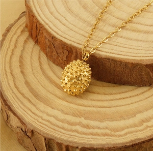 Detailed view of 18k gold plated durian pendant on natural wood background for necklace