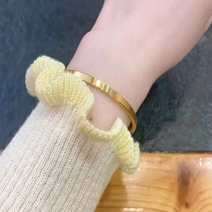 Detailed view of a minimalist gold-plated stainless steel bangle on a female wrist