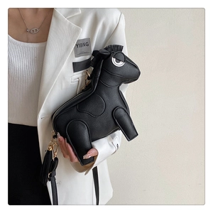 Detail of creative black leather horse-shaped crossbody bag with gold hardware and tassels