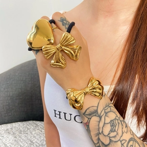 Three-piece set of golden stainless steel hair ties featuring heart and bow designs
