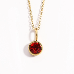 Close-up of golden birthstone necklace with a round red ruby pendant in bezel setting