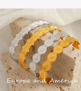 Detail of gold and silver bangles with star relief and ripple textures on stone base
