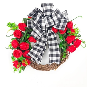 Detailed view of heart-shaped rattan wreath with red roses and plaid bow decoration