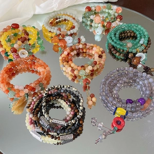 Nahaufnahme bunter mehrlagiger Perlenarmbänder mit Vintage-Blumenanhängern und Quasten