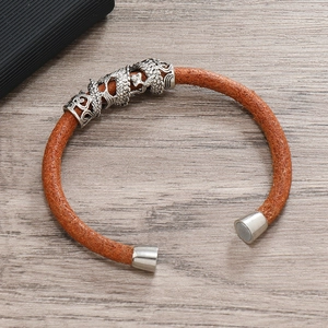 Close-up of brown braided leather bracelet featuring a silver dragon charm and magnetic clasp