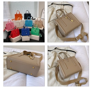 Detailed view of square crossbody bag showing gold feet and wide adjustable shoulder strap