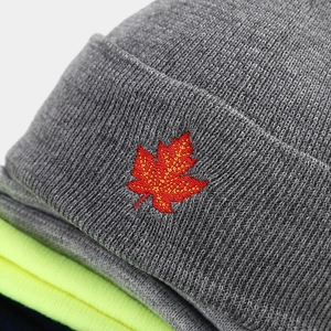 Dark grey knitted beanie featuring red maple leaf embroidery with thick knit texture
