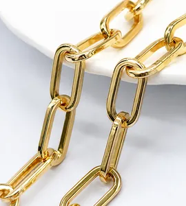 Macro view of golden paperclip chain links with high metallic luster on white tray