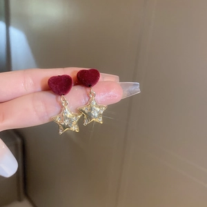 Dettaglio degli orecchini a cuore rosso con pendenti a stella dorati e strass luminosi