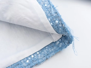 Detail shot of blue tweed jacket featuring transparent sequins and white plain lining