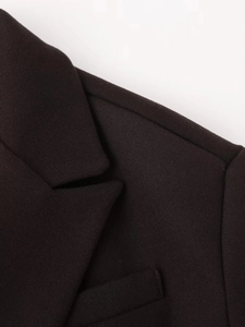 Close-up detail of the black wool fabric collar and shoulder on a minimalist jacket
