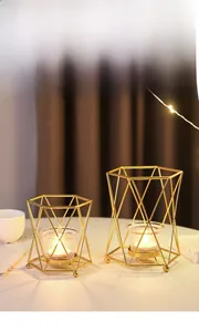 Detail of geometric gold wire candle holders with glass cups and glowing tea lights