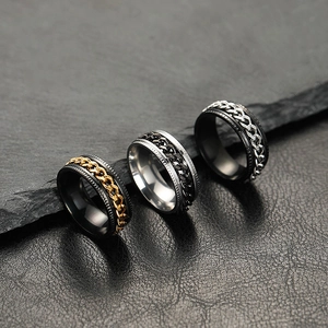 Macro view of rotating chain rings in black, gold and silver on a dark stone background