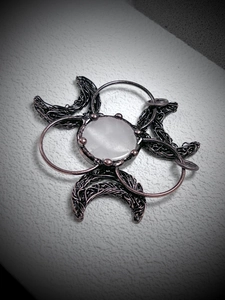 Close-up of bronze wire wrapped biohazard pendant with white quartz crystal stone