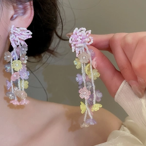 Primer plano de pendientes de cuentas con flores de cristal pastel de estilo bohemio