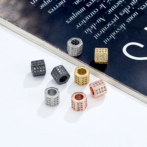 Micro-paved hexagonal cylinder beads in gold, silver, and black on an open book
