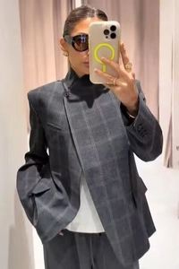 Dettaglio del blazer grigio a quadri con collo alla coreana e chiusura asimmetrica