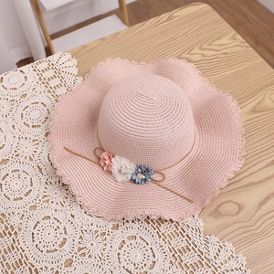 Détail du chapeau de paille rose avec fleurs décoratives et bordure festonnée tissée