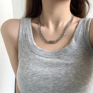 Close-up of a silver Cuban chain necklace with rectangular pendant worn by a model