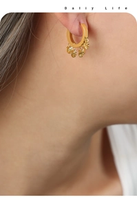 Détail de boucles d'oreilles créoles dorées en U avec pendentifs disques rayés