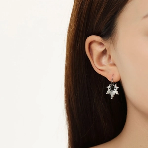 Detail of silver sunburst earrings with black stone on a model for French chic style