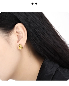 Detail of gold irregular crumpled texture earring worn by a model for a modern look