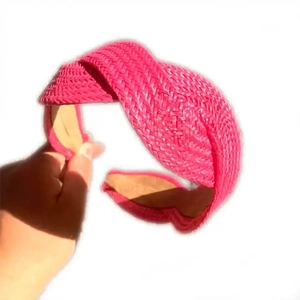 Macro detail of hand-woven straw braid texture on a magenta fashion headband