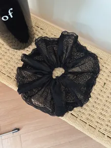 Detailed view of large black lace scrunchie with intricate floral embroidery and wavy edges