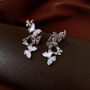 Boucles d'oreilles papillon en argent avec zircon et nacre sur surface en cuir