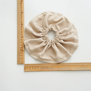 Oversized beige fabric scrunchie shown with a wooden ruler to display the 20cm diameter size