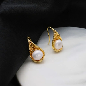 Vintage bird nest pearl earrings in 18k gold finish on black silk and marble base