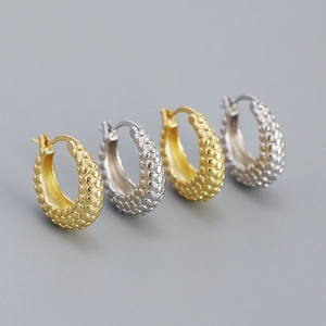 Detail of four U-shaped gold and silver earrings with textured hammered finish surface