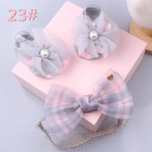 Detail of grey baby socks with mesh flowers and pink plaid bow headband in gift box