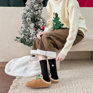 Dettaglio di calze natalizie nere a maglia con ricamo Babbo Natale in scena invernale
