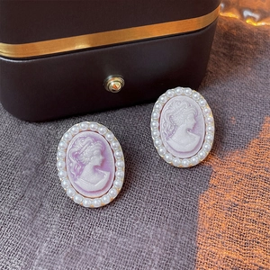 Close-up of vintage style purple cameo earrings with elegant pearl border