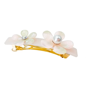 Detail of elegant gold metal hair clip with pearlescent resin flowers and pearls