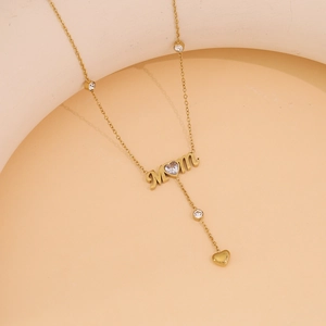 Macro detail of gold Mom pendant with heart charm and zircon stones on double layer chain