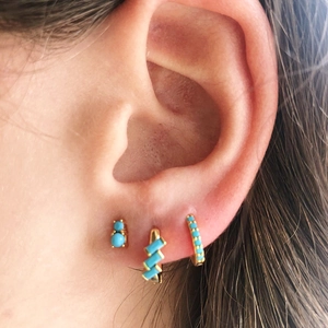 Close-up of gold geometric earrings set with vibrant turquoise rectangular gemstones