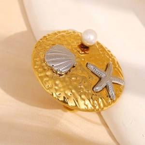 Detailed macro view of 18K gold starfish and pearl accents on a hammered metal ring
